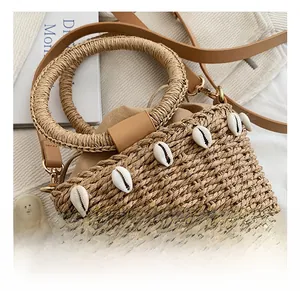 Detailed close-up of woven straw bag with decorative white shells and drawstring lining