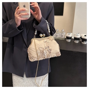 Détail du sac coquillage crème avec broderies florales et poignée élégante en perles