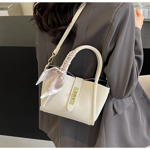 Détail d'un sac à main blanc en cuir litchi avec fermoir doré et poignée en soie