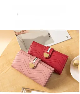 Detail of pink and red long wallets featuring V-quilted faux leather and heart metal buckle