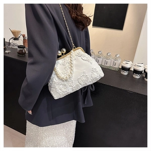 Détail de la broderie de fleurs en dentelle blanche sur sac de soirée avec anse en perles