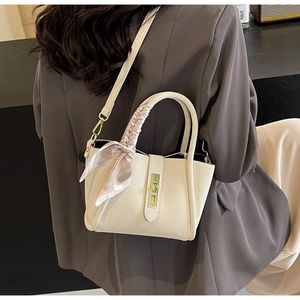 Détail du sac crème en cuir grainé avec foulard en soie rose et fermoir métallique
