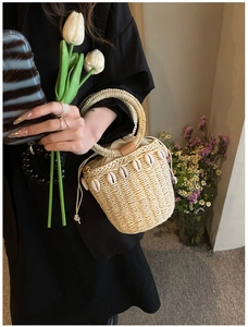 Detail of straw bucket bag with shell fringe and reinforced round handle for summer