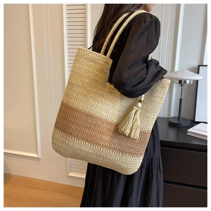 Detail of a large woven tote bag with gradient stripes and stylish tassel decoration