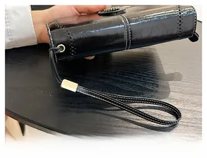 Detail of black oil wax leather wallet featuring white contrast stitching and hand strap
