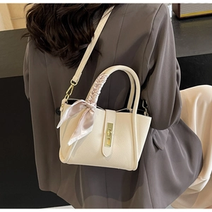 Détail du sac seau en cuir litchi crème avec foulard en soie et fermoir doré