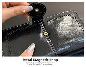 Detail of hardware snap fastener on black oil wax leather wallet with white stitching