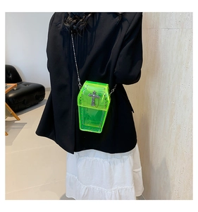 Neon green coffin-shaped cross-body bag with silver cross and rivet details shown on model