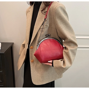 Detail of red quilted shell bag with silver clasp and chain strap worn by a model