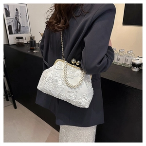 Détail de sac à main en dentelle blanche avec anse perlée et chaîne dorée fine