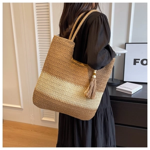 Detailed texture of large striped woven tote bag with fringe tassel on a model