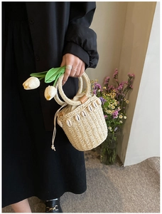 Detailed view of handwoven straw bucket bag with natural shell accents and ring handles