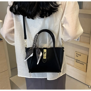 Détail d'un sac seau noir en cuir avec foulard en soie imprimé fashion sur la poignée