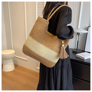 Detail of a large woven tote bag featuring color-block design and tassel with wooden beads