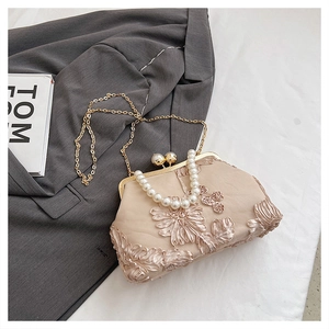 Détail du sac de soirée avec broderie florale en dentelle, poignée en perles et chaîne