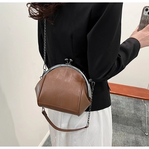 Rear view of model wearing a vintage brown shell bag with metal chain strap and cross stitching