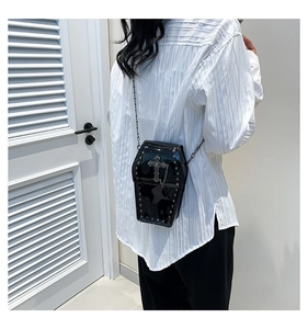 Detail view of gothic coffin-shaped crossbody bag with rivets and cross on model
