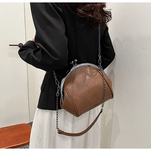Detail of dark brown vintage clasp bag with cross-stitch design on a female model
