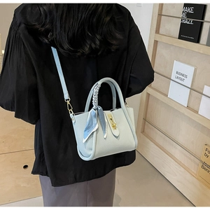 Sac seau bleu clair à grain litchi porté par un mannequin dans une bibliothèque calme