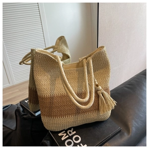 Detail of hand-woven tote bag showing gradient straw texture and decorative fringe tassel