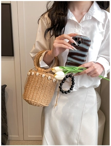 Detail of straw bucket bag with white shell decorations and drawstring closure