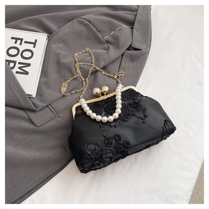 Détail du sac de soirée en satin noir avec broderie florale et fermoir en métal doré