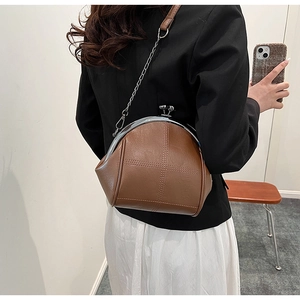 Detailed view of brown crossbody shell bag with cross-stitch pattern and silver chain strap