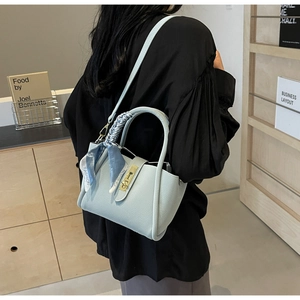 Détail du sac seau bleu clair à motif litchi avec foulard mode et fermoir en métal doré