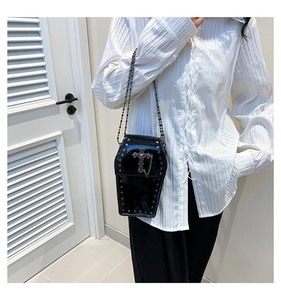 Close-up of goth coffin crossbody bag with silver cross pendant and metal rivet details