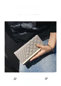Detail view of a light gray quilted leather long wallet with metallic bar decoration