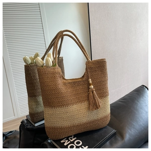 Detail of color-block woven straw tote bag with side tassels and wooden bead charm