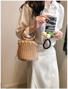 Detail of hand-woven straw bucket bag with shell fringe trim and top handle for beach vacations