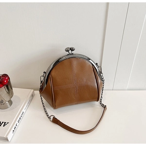 Macro detail of brown shell bag showing retro metal clasp and lychee grain leather