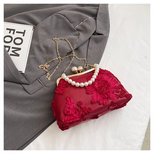 Détail de broderie florale rouge sur sac coquille avec anse perle et chaîne dorée