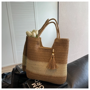 Detail of woven straw tote bag with brown tassels and wooden beads for summer holidays