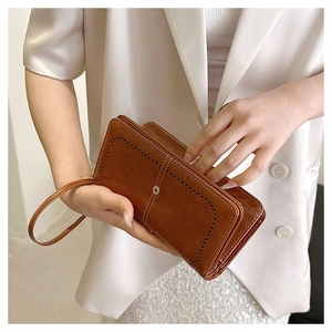 Detail of vintage brown oil wax leather wallet featuring hollow patterns and wristlet strap