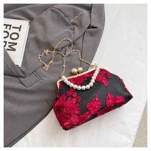 Détails de la broderie florale 3D rouge et de la poignée en perles sur sac en satin noir