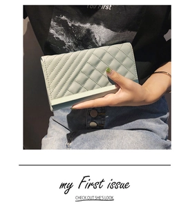Detail of mint green quilted long wallet held by hands, showcasing its slim trifold design