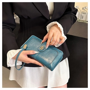 Detail of teal oil wax leather wallet with retro sunflower clasp and contrast stitching