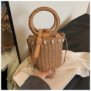 Detail of straw bucket bag featuring natural seashells and woven top handle for summer