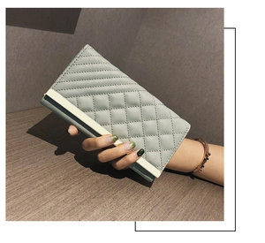 Detail of light green quilted leather long wallet with gold metal trim and elegant texture