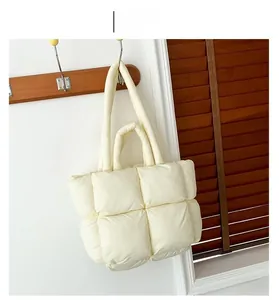 Detail of white quilted puffer tote bag hanging on hook showing high-quality nylon texture