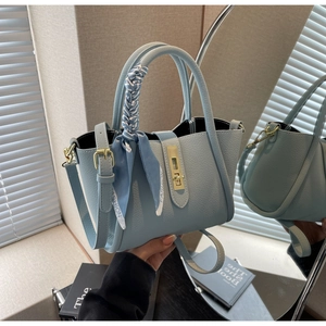 Détail du sac seau bleu clair à motif litchi avec foulard en soie et boucle en métal doré