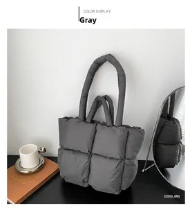 Detail of grey quilted puffer tote bag with square pattern on wooden surface