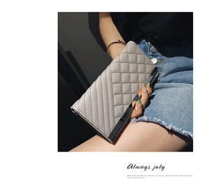 Detail of grey quilted long wallet featuring diamond stitching and metal trim closure