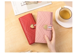Detail of red and pink long wallets with V-shaped stitching and heart metal buckles