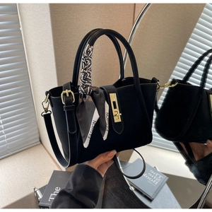 Détail du sac seau noir en cuir grainé avec foulard en soie et fermoir carré doré