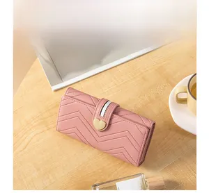 Pink chevron quilted leather wallet with gold heart buckle on a stylish wooden table