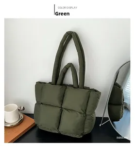 Detailed close-up of dark green quilted puffer tote bag with square stitching and soft handle
