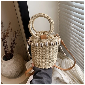 Detailed view of straw bucket bag with shell accents and circular woven handles